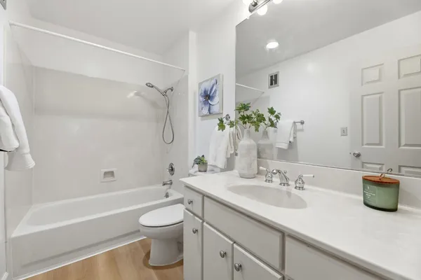 a bathroom with a granite countertop sink a toilet a tub and shower