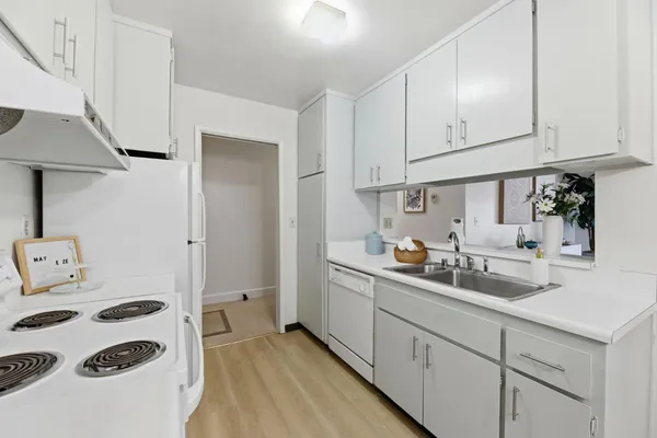a kitchen with sink a stove and white cabinets