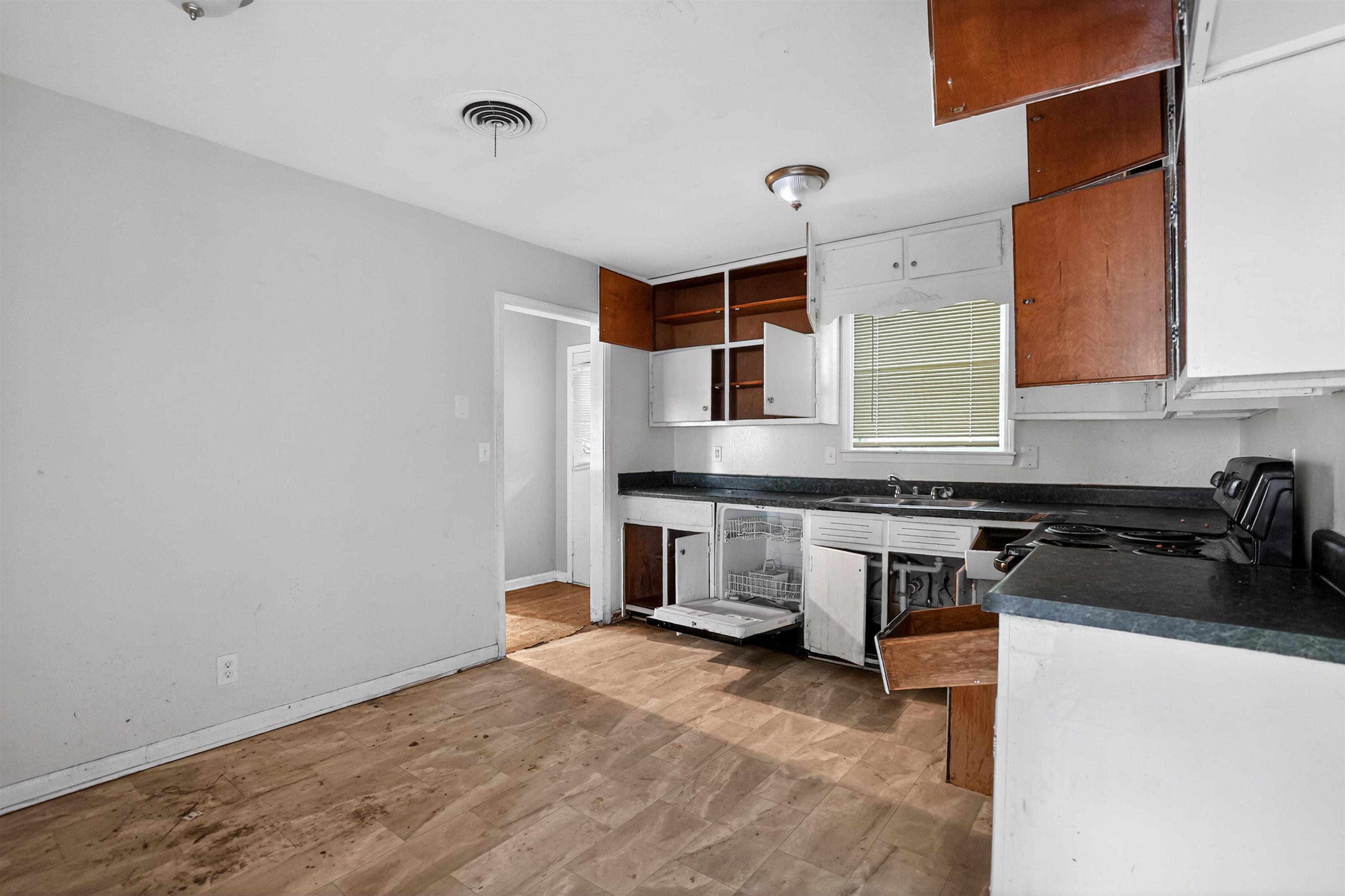 1890 Pennel Road Memphis, TN 38116 - Photo 19 of 25 Kitchen space featuring wood-finish flooring, a window with blinds, and white base cabinetry with dark countertops