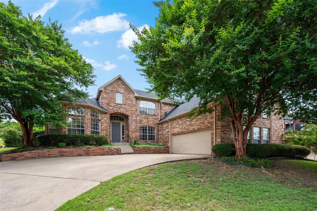 5607 Ranger Drive Rockwall, TX 75032 - Photo 40 of 40 Brick facade residence featuring an arched entry, multiple large windows, a concrete driveway, and established trees