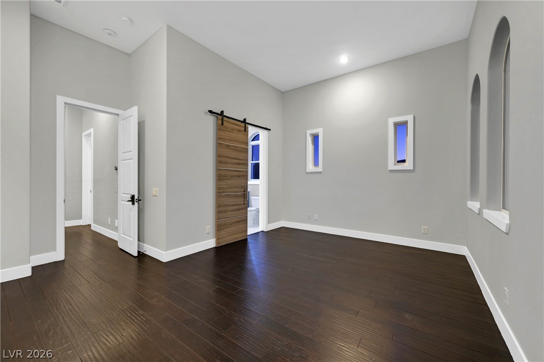 6 Rue Du Ville Henderson, NV 89011 - Photo 68 of 99 This expansive room features rich wood flooring and a modern barn door, creating a sophisticated aesthetic.
