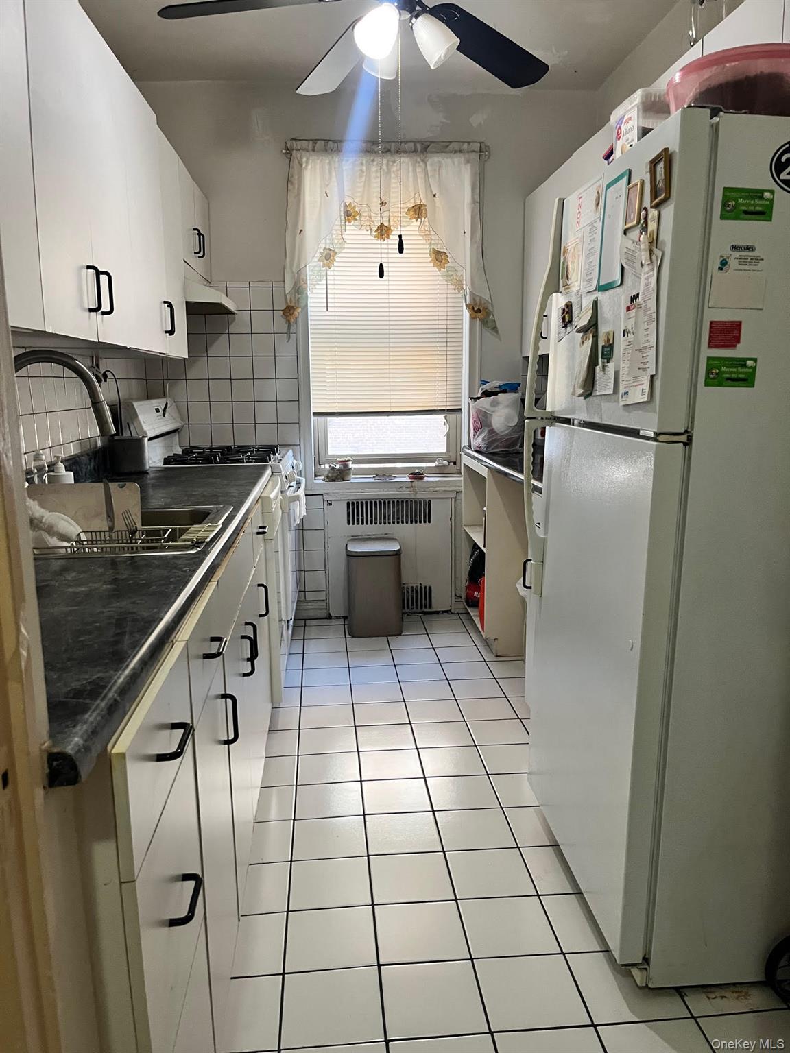 84-49 168th Street, Unit 2B Queens, NY 11432 - Photo 12 of 12 a kitchen with granite countertop a refrigerator and a stove top oven
