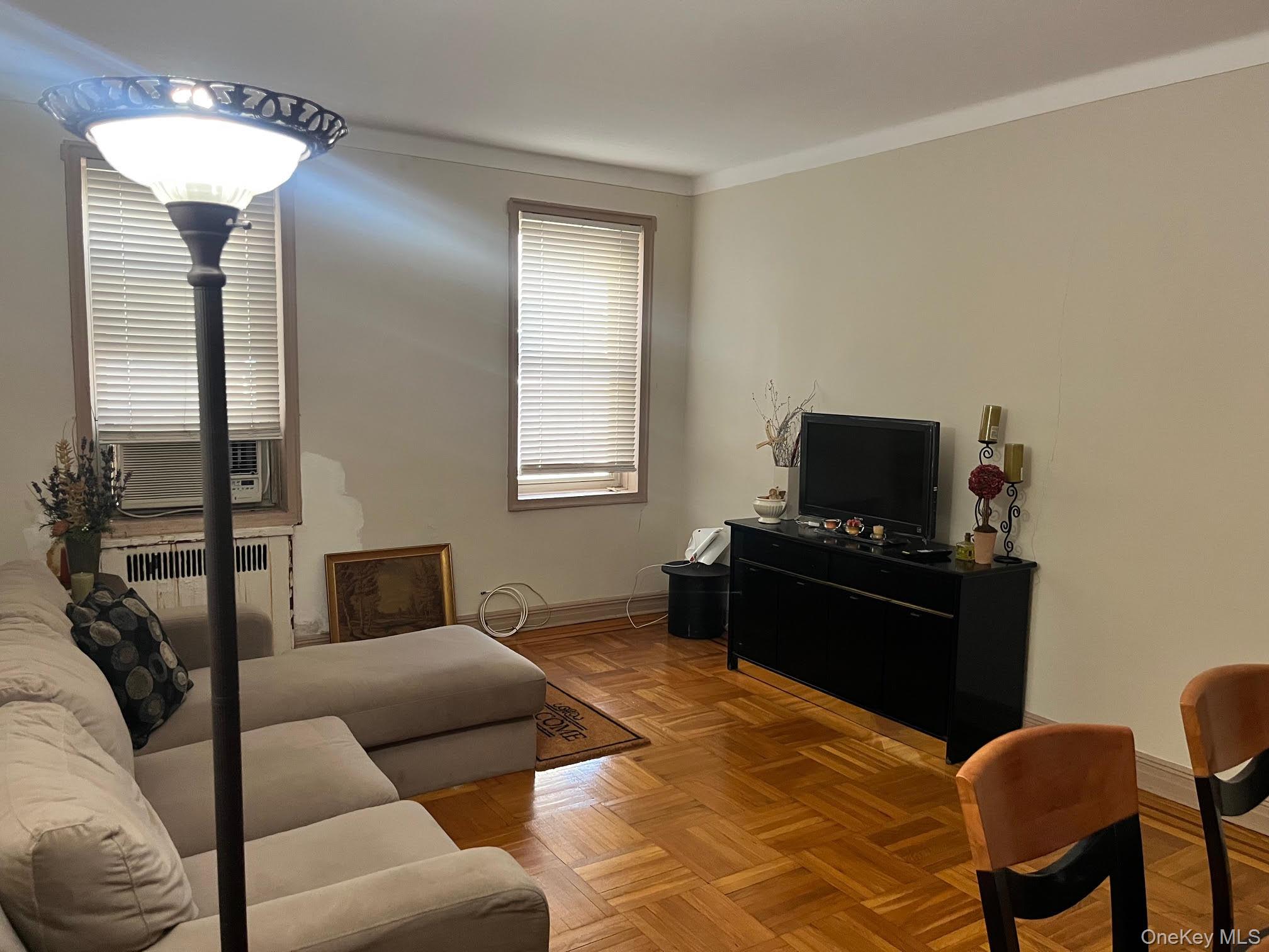 84-49 168th Street, Unit 2B Queens, NY 11432 - Photo 8 of 12 a living room with furniture and a flat screen tv