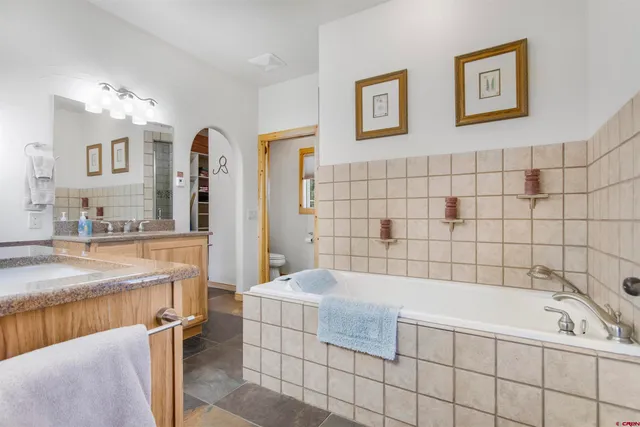 a spacious bathroom with a tub sink and mirror