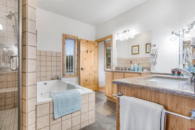 a spacious bathroom with a granite countertop sink a mirror and shower
