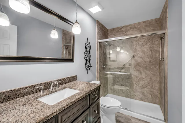a bathroom with a granite countertop sink toilet and shower