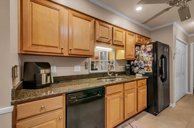 a kitchen with granite countertop stainless steel appliances a sink window and cabinets