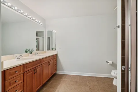 a spacious bathroom with a double vanity sink a large mirror and toilet