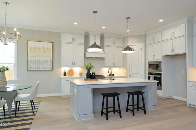 a kitchen with kitchen island granite countertop a table chairs sink and cabinets
