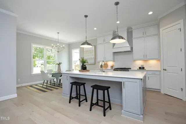 a kitchen with kitchen island a dining table chairs and white cabinets