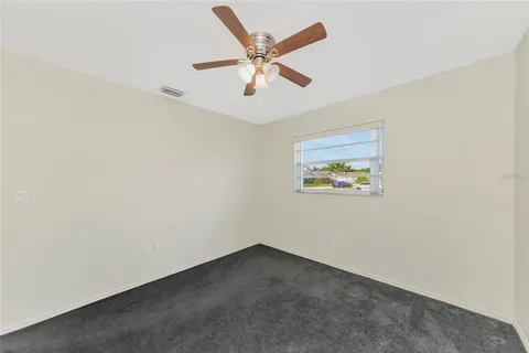 an empty room with a ceiling fan and window