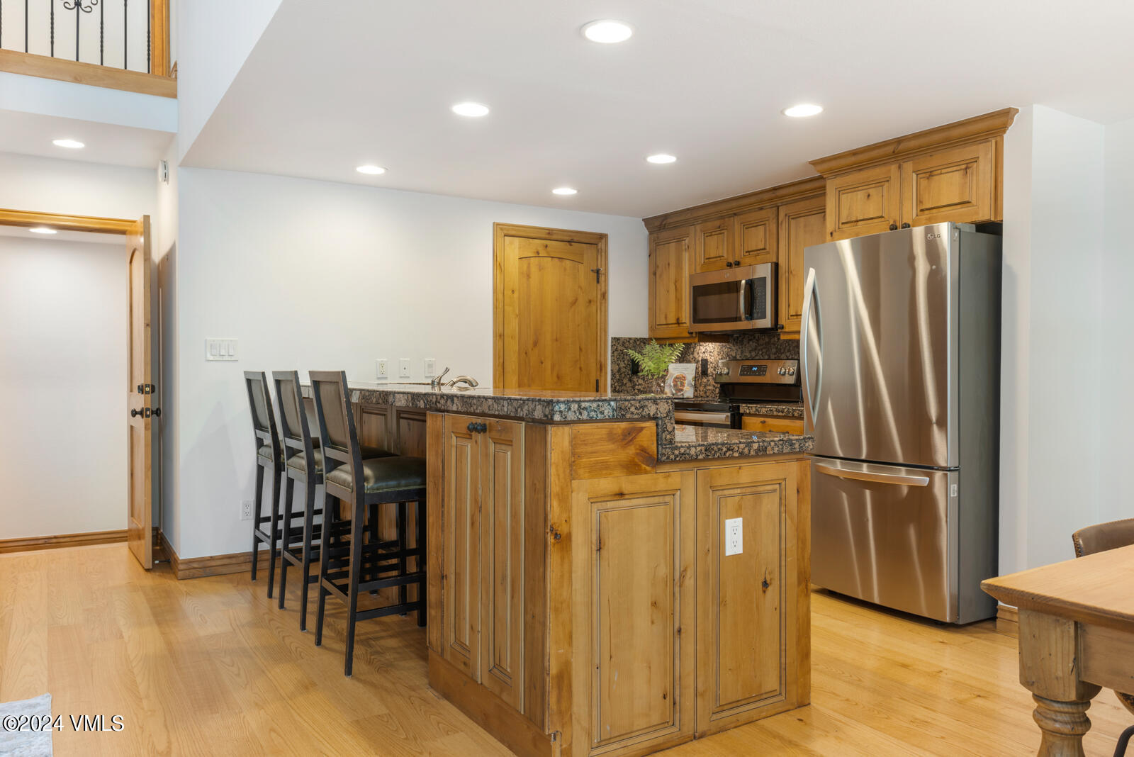 4552 Meadow Drive, Unit 24 Vail, CO 81657 - Photo 7 of 31 a kitchen with stainless steel appliances granite countertop a refrigerator a stove a sink a dining table and chairs with wooden floor