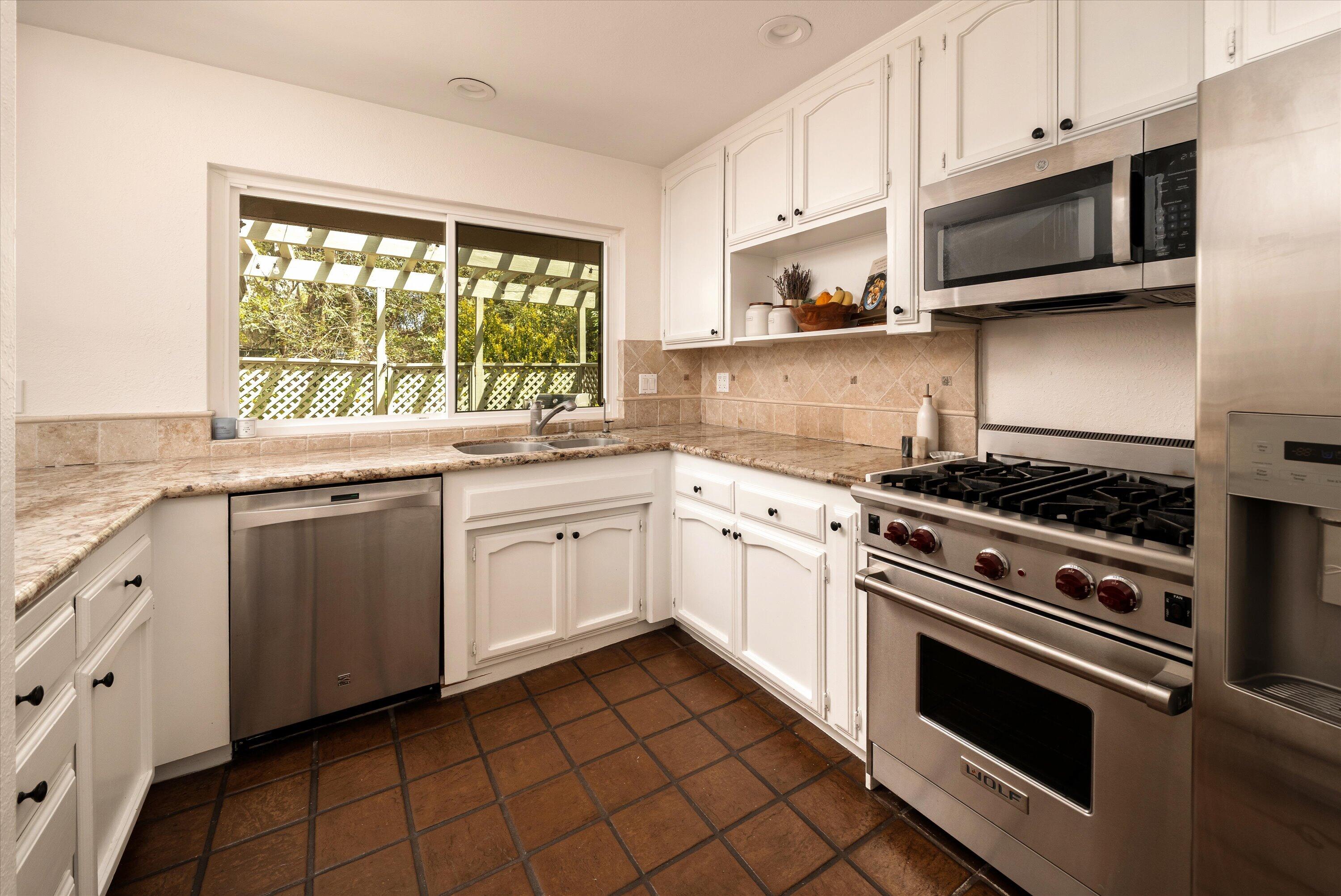 276 North La Cumbre Road Santa Barbara, CA 93110 - Photo 6 of 16 a white kitchen with granite countertop a stove top oven microwave and cabinets