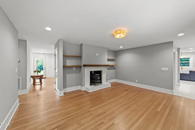 a view of an empty room with wooden floor and a fireplace