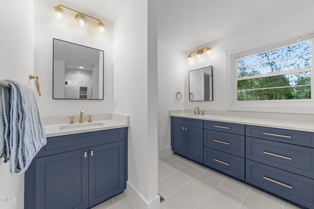 a bathroom with a granite countertop double vanity sink and mirror with window