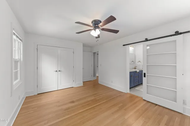 a view of empty room with wooden floor and fan