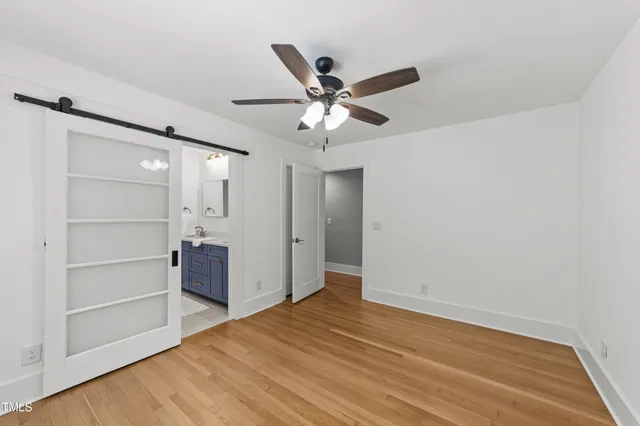a view of empty room with wooden floor and fan