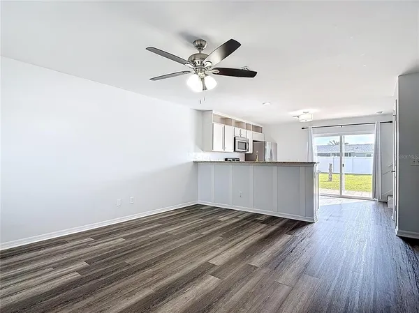 a view of kitchen and empty room with wooden floor