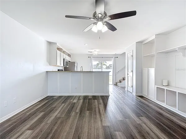 a view of a room with wooden floors and ceiling fan