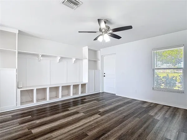 a view of empty room with wooden floor and fan