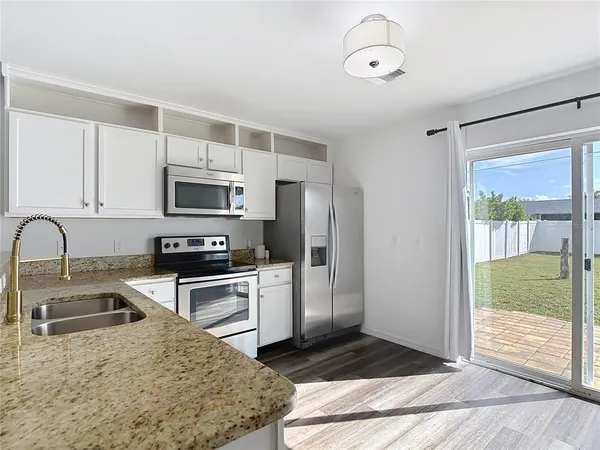 a kitchen with stainless steel appliances granite countertop a stove a sink and a refrigerator