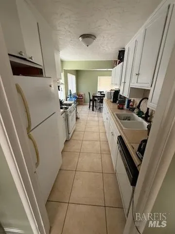 a kitchen with stainless steel appliances a refrigerator a sink a stove and white cabinets