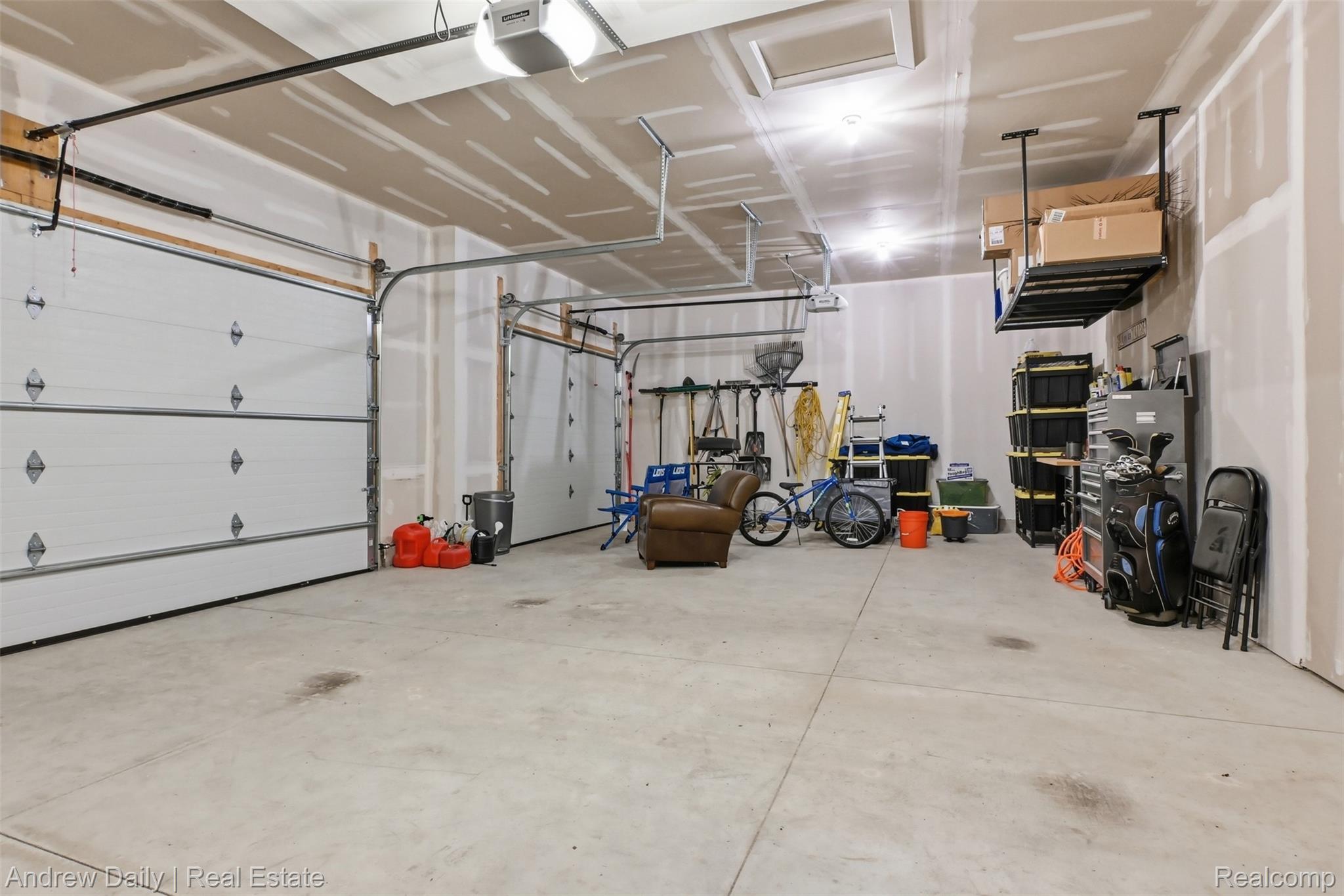 4661 Spears Road Pinckney, MI 48169 - Photo 42 of 56 Spacious 3-car garage featuring a concrete floor, two overhead doors with automatic openers, and overhead storage racks