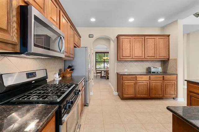 a kitchen with stainless steel appliances granite countertop a sink a stove and a microwave