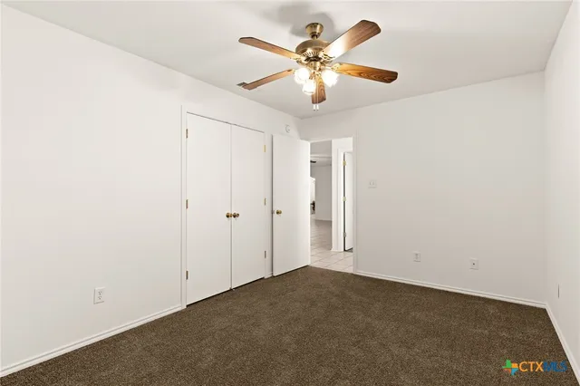 an empty room with a chandelier fan and a window