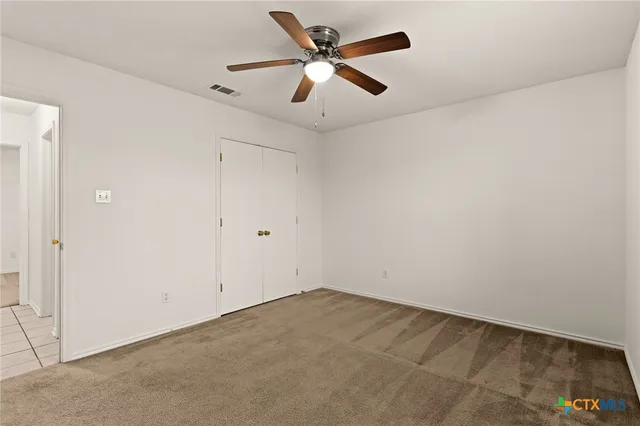 an empty room with ceiling fan and window