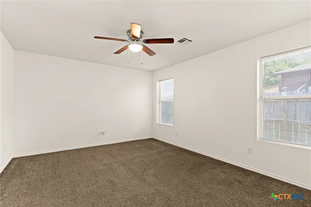 an empty room with windows and fan