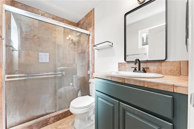 a bathroom with a sink a toilet a mirror and shower