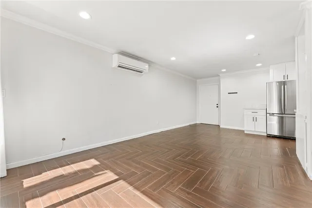 an empty room with wooden floor and natural light