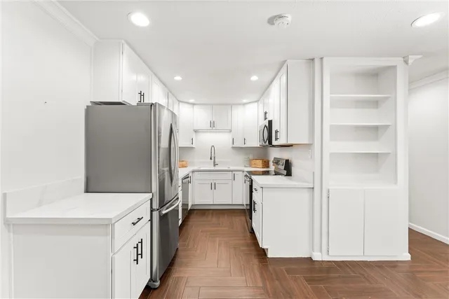 a kitchen with a refrigerator a stove top oven and white cabinets