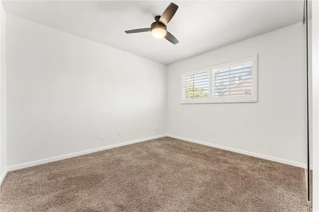 an empty room with a window and a ceiling fan