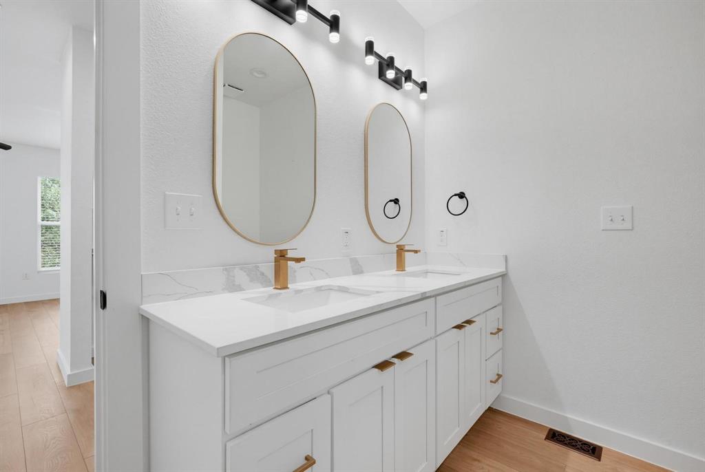 504 South O Connor Road Irving, TX 75060 - Photo 15 of 23 Dual vanity with white cabinetry, gold-finish hardware, and a white countertop with integrated sinks