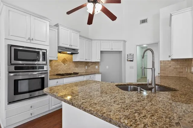 a kitchen with granite countertop white cabinets and white appliances