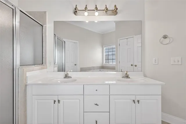 a spacious bathroom with a double vanity sink a mirror and a bathtub