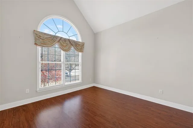 an empty room with wooden floor exposed radiator and a window