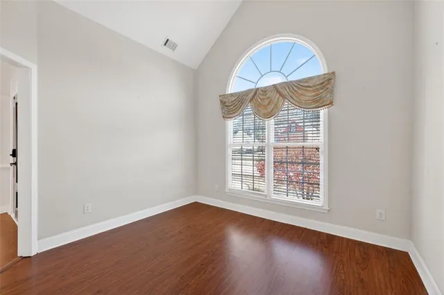 an empty room with wooden floor fan and windows
