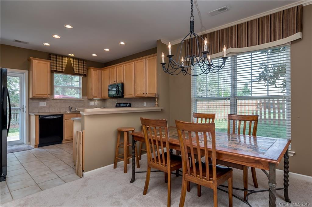 134 Whitley Mills Road, Unit 78 Fort Mill, SC 29708 - Photo 7 of 25 a kitchen with kitchen island granite countertop wooden cabinets dining table and chairs