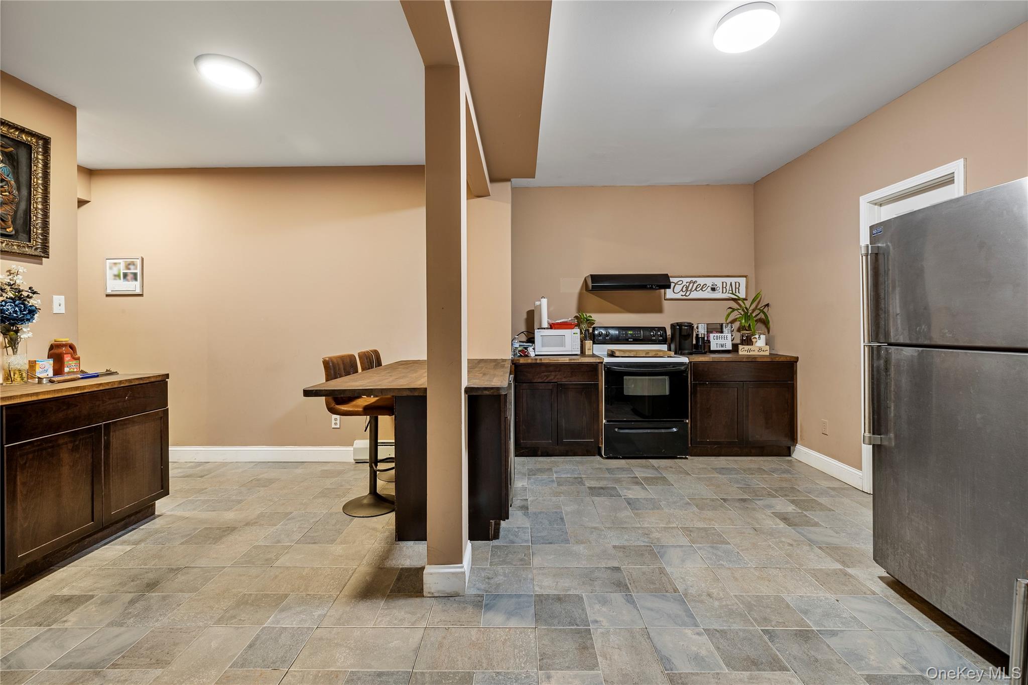 35 Pierce Road Stony Point, NY 10980 - Photo 32 of 45 Kitchen with dark brown cabinets, freestanding refrigerator, stone finish flooring, black electric range, and a kitchen bar
