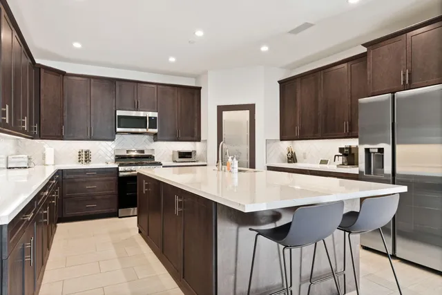 a kitchen with stainless steel appliances a stove top oven a refrigerator a sink and dishwasher with wooden cabinets