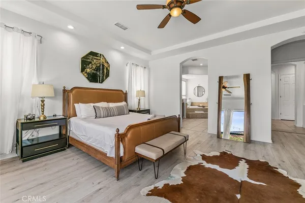 a spacious bedroom with a bed a couch and a chandelier