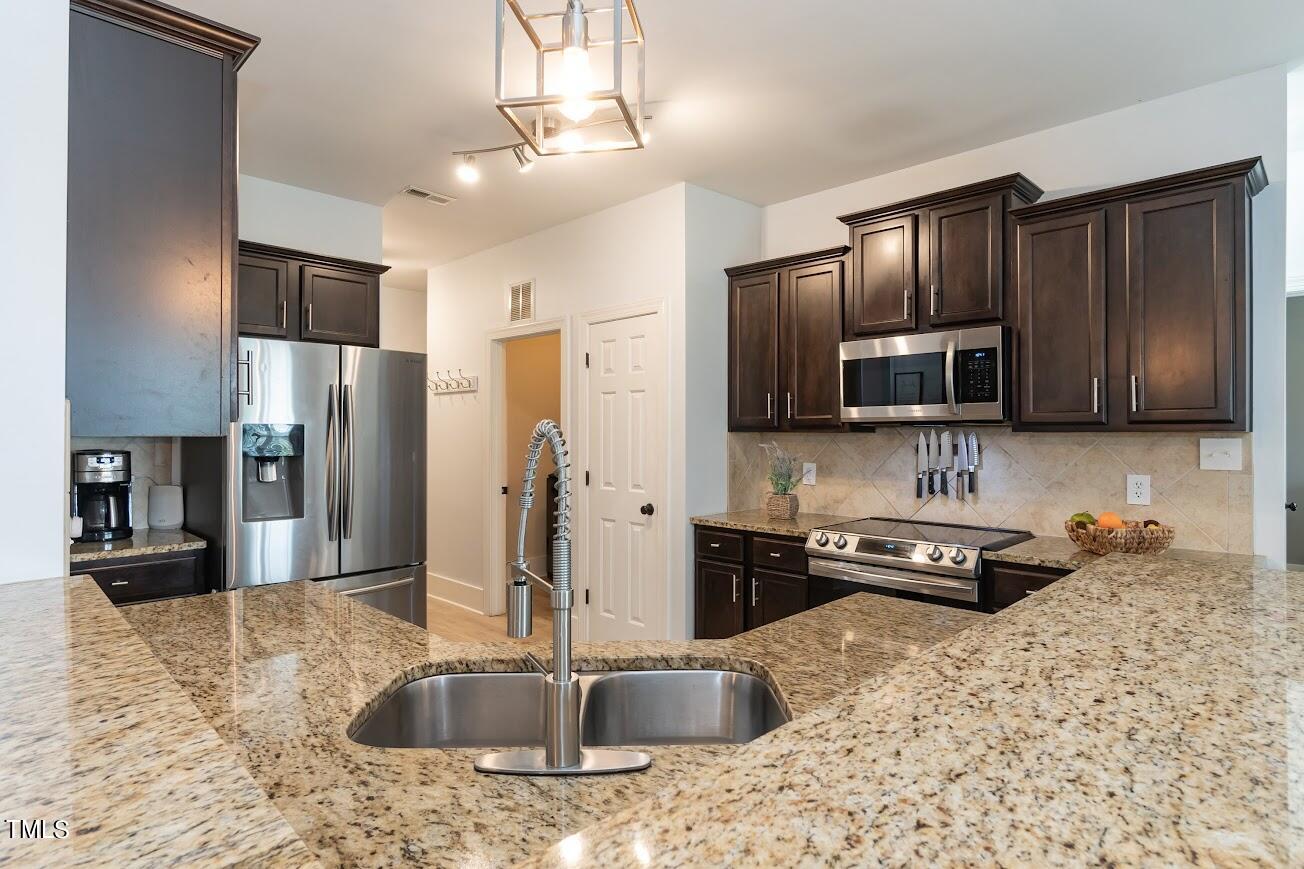 91 Colson Drive Garner, NC 27529 - Photo 17 of 46 a kitchen with stainless steel appliances granite countertop a refrigerator a stove a sink a microwave and wooden cabinets