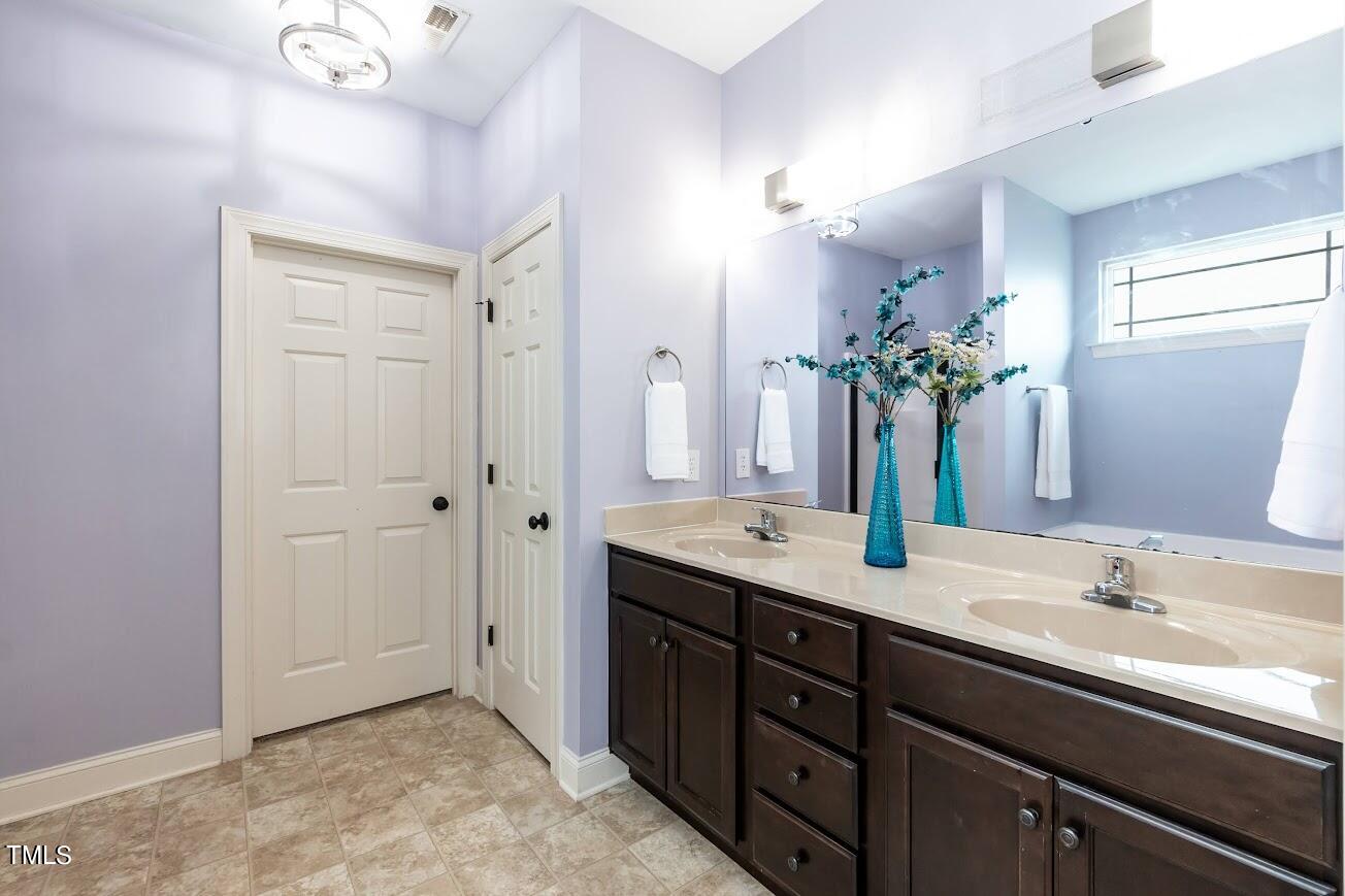 91 Colson Drive Garner, NC 27529 - Photo 27 of 46 a spacious bathroom with a granite countertop sink and a mirror