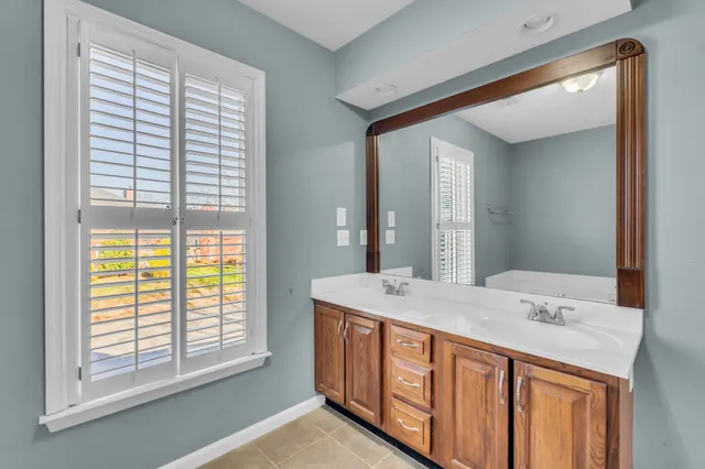 a bathroom with a granite countertop sink and a large mirror next to a window