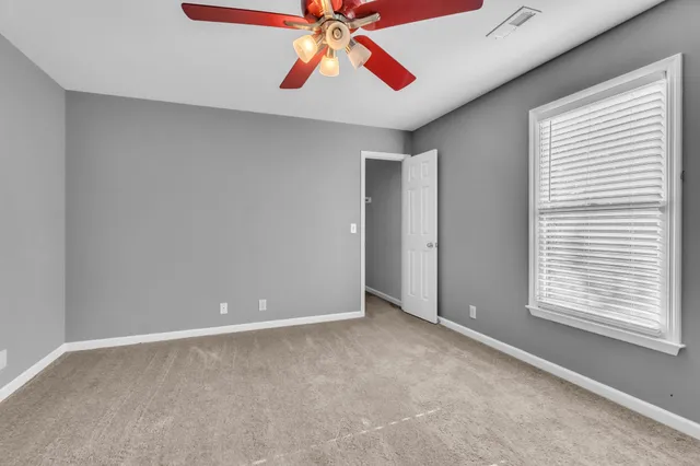 a view of an empty room with window and a chandelier fan