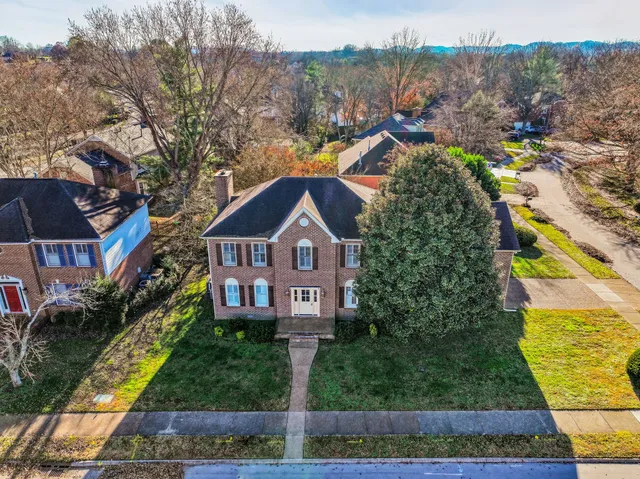 a front view of a house with a yard and large tree