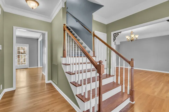 a view of staircase with wooden floor and a chandelier